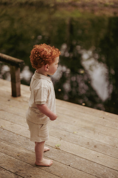 Jongen kijkt naar het water in kinderkleding van Mr. Loutre