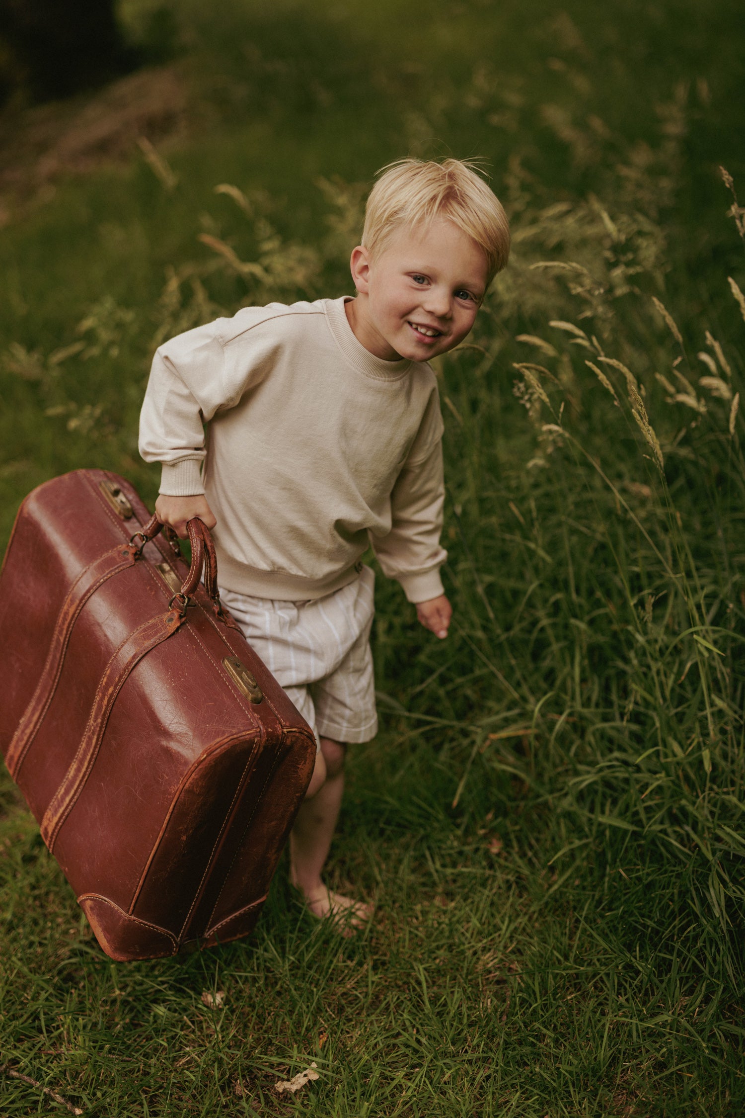 Jongen in kinderkleding van jongensmerk Mr. Loutre op pad met een grote koffer